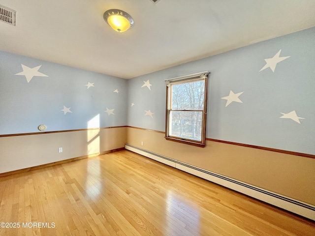 empty room featuring wood-type flooring and baseboard heating