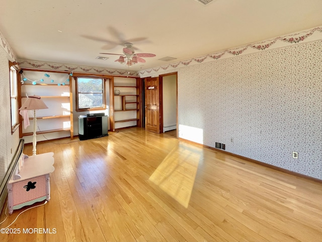 unfurnished living room with ceiling fan, a baseboard heating unit, and light hardwood / wood-style floors