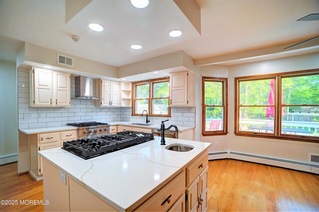 705 Princeton Rd, Lanoka Harbor, NJ 08734 - kitchen with wall chimney exhaust hood, a sink, light wood-style flooring, a kitchen island with sink, and light stone counters