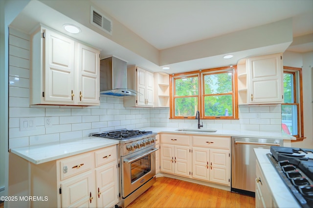 705 Princeton Rd, Lanoka Harbor, NJ 08734 - kitchen featuring appliances with stainless steel finishes, wall chimney range hood, open shelves, a sink, and light wood-style flooring