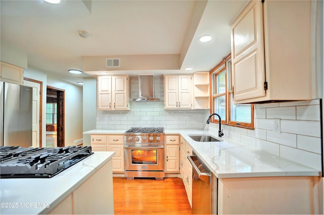 705 Princeton Rd, Lanoka Harbor, NJ 08734 - kitchen with stainless steel appliances, wall chimney exhaust hood, a sink, light wood-style flooring, and light stone counters