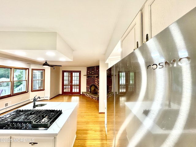 705 Princeton Rd, Lanoka Harbor, NJ 08734 - kitchen with light wood-style floors, a brick fireplace, french doors, white cabinets, and light countertops