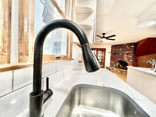 705 Princeton Rd, Lanoka Harbor, NJ 08734 - kitchen view of ceiling fan, a brick fireplace, light stone countertops, open shelves, and a sink