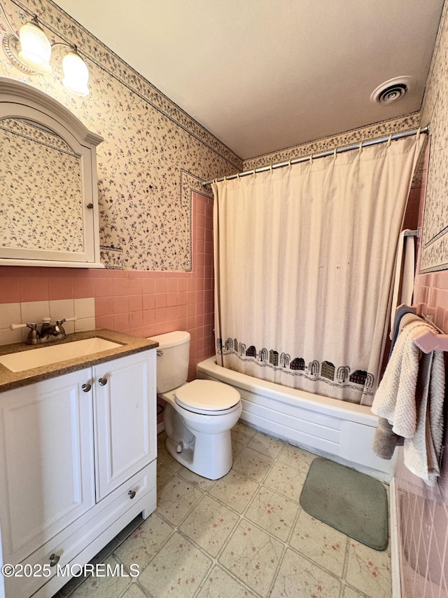 full bathroom with shower / bath combo, tile walls, vanity, and toilet