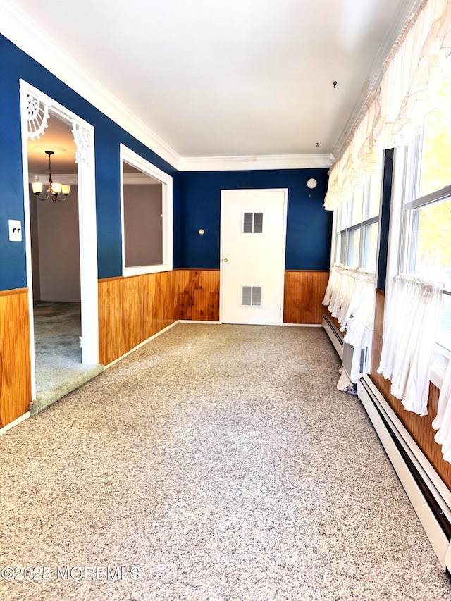 carpeted spare room featuring an inviting chandelier, a baseboard radiator, and crown molding