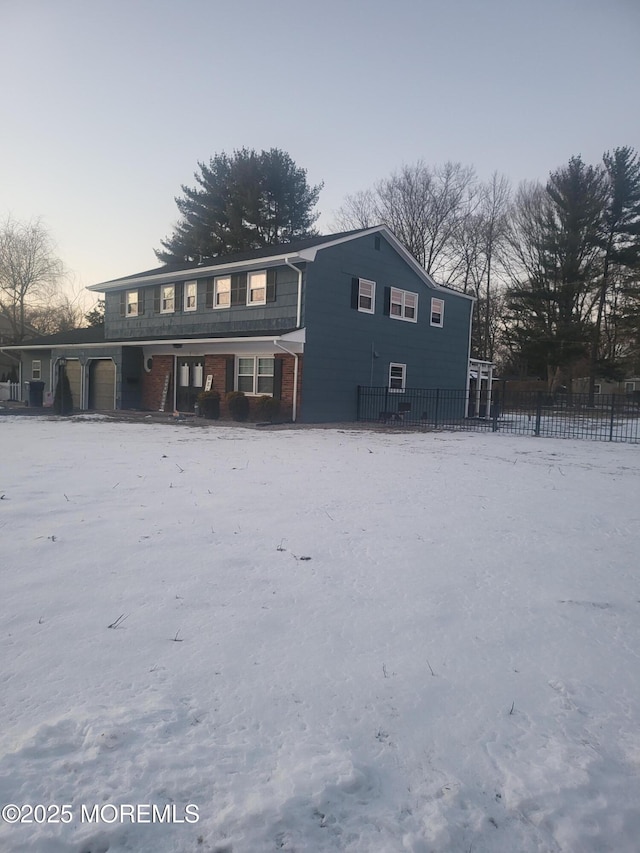 snow covered back of property featuring a garage