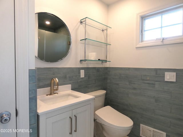 bathroom featuring vanity, tile walls, and toilet