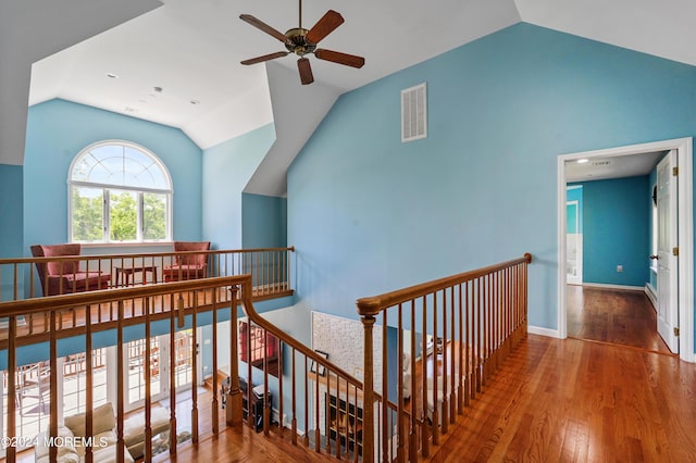 hall featuring baseboards, visible vents, wood finished floors, an upstairs landing, and high vaulted ceiling