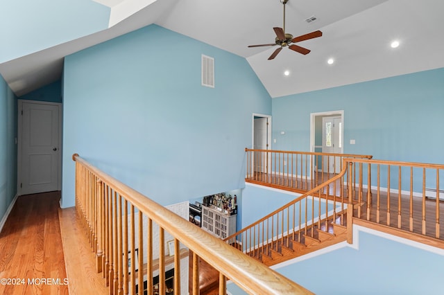 hall with visible vents, vaulted ceiling, wood finished floors, and an upstairs landing