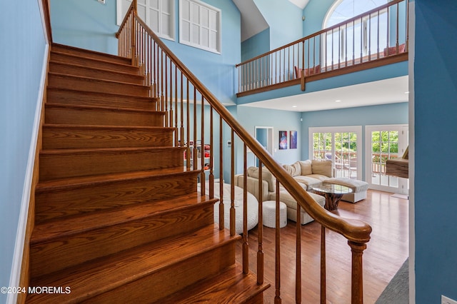 stairway featuring a towering ceiling, wood finished floors, and recessed lighting