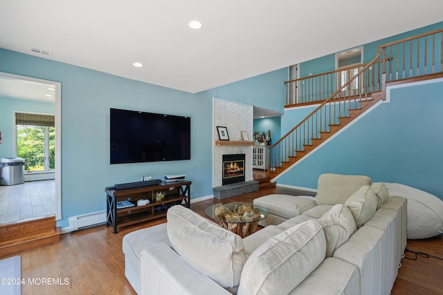 living area featuring a baseboard heating unit, stairs, wood finished floors, and visible vents