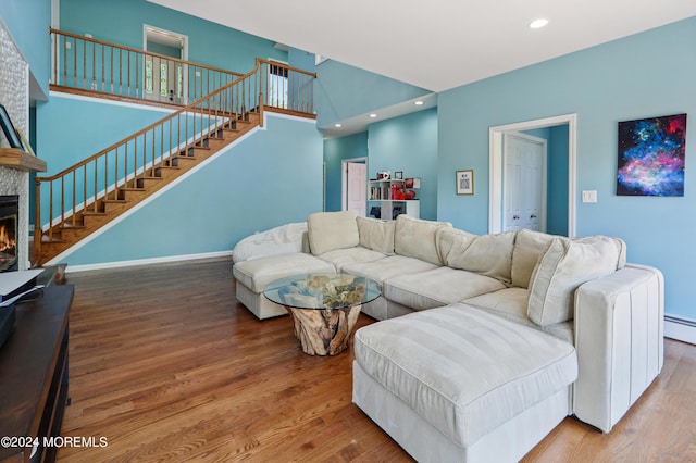 living area with recessed lighting, a large fireplace, stairway, and wood finished floors