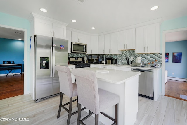 kitchen featuring white cabinets, a kitchen island, appliances with stainless steel finishes, and decorative backsplash