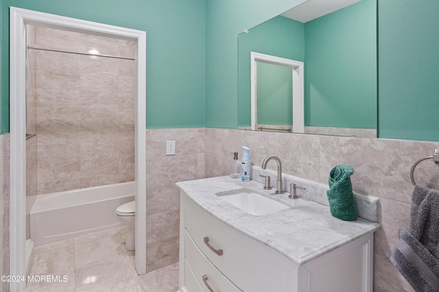 bathroom with wainscoting, toilet, shower / tub combination, vanity, and tile walls