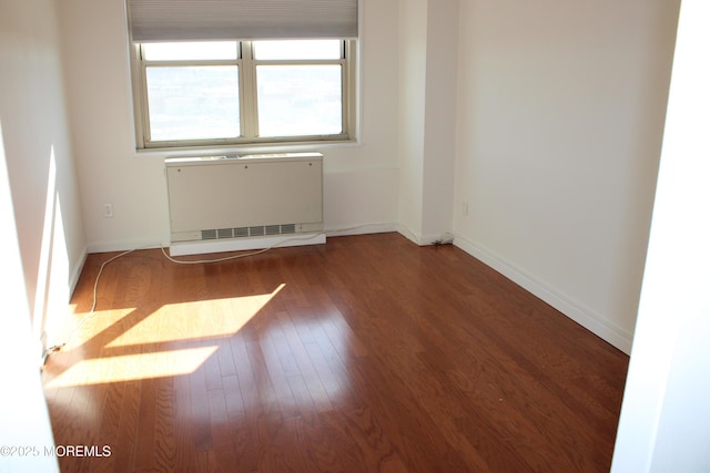 unfurnished room featuring radiator heating unit and hardwood / wood-style floors