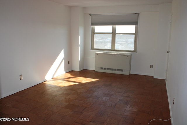 spare room with radiator and dark parquet flooring