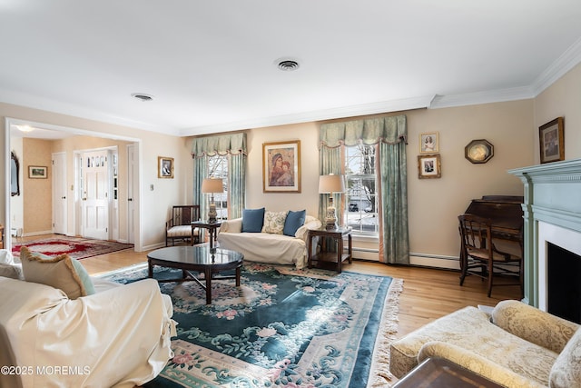 living room featuring a baseboard heating unit, ornamental molding, and light wood-type flooring