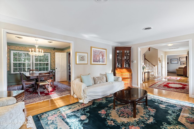 living room with wood-type flooring, ornamental molding, and a notable chandelier