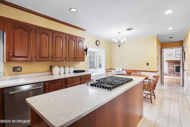 kitchen with a fireplace, decorative light fixtures, a chandelier, a center island, and stainless steel appliances