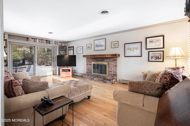 living room featuring hardwood / wood-style floors, crown molding, a baseboard radiator, and a brick fireplace