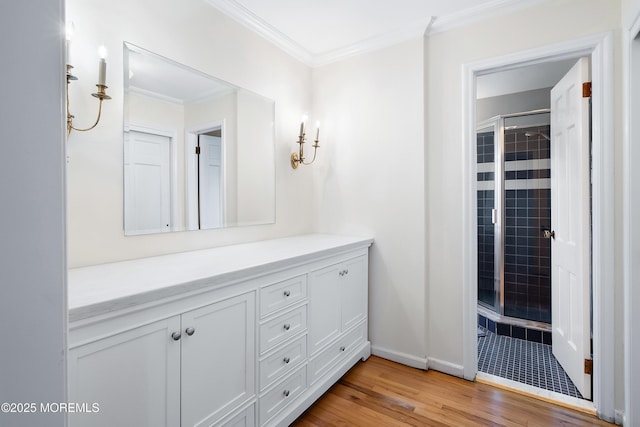 bathroom featuring crown molding, hardwood / wood-style floors, vanity, and a shower with shower door