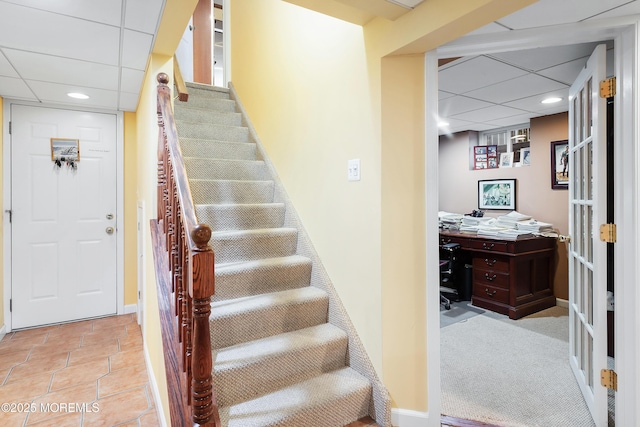 staircase featuring a drop ceiling, french doors, and carpet