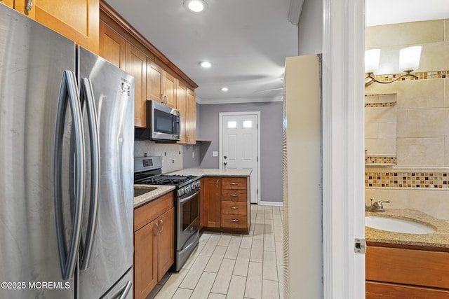 kitchen with appliances with stainless steel finishes, sink, light stone counters, and decorative backsplash