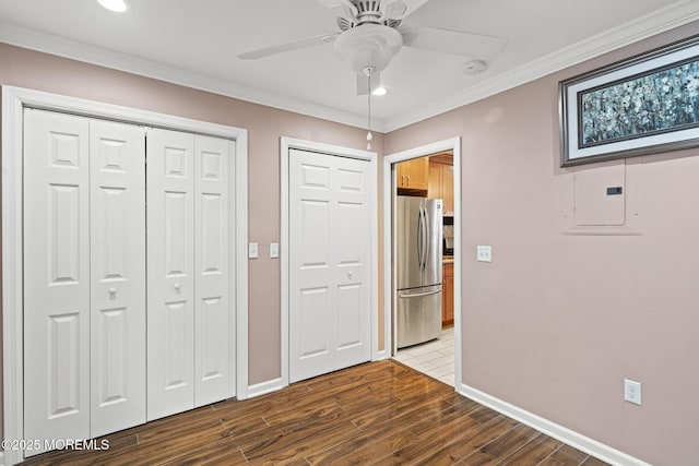 unfurnished bedroom with stainless steel refrigerator, ornamental molding, electric panel, two closets, and hardwood / wood-style flooring