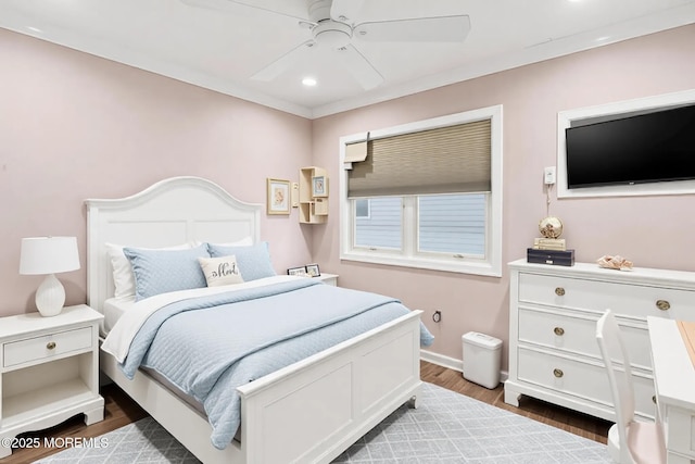 bedroom featuring a ceiling fan, crown molding, baseboards, and wood finished floors