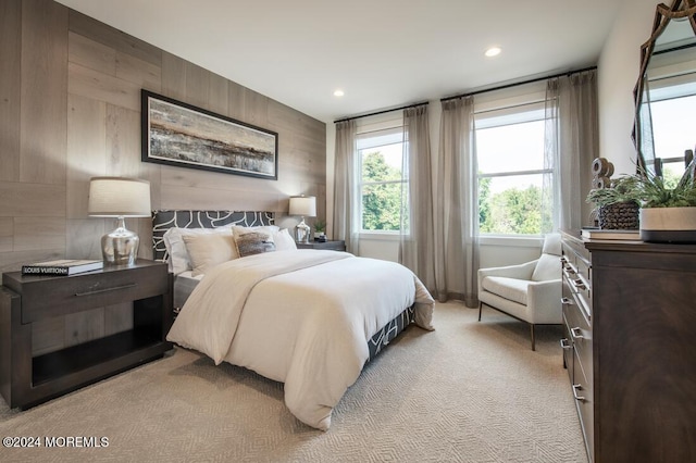 bedroom featuring light carpet and wooden walls