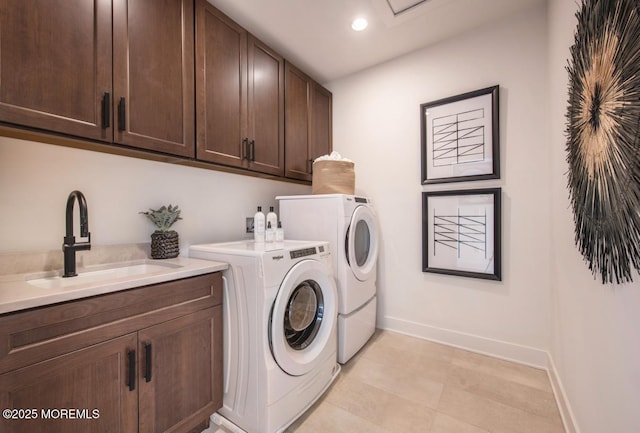 clothes washing area with cabinets, washing machine and dryer, and sink