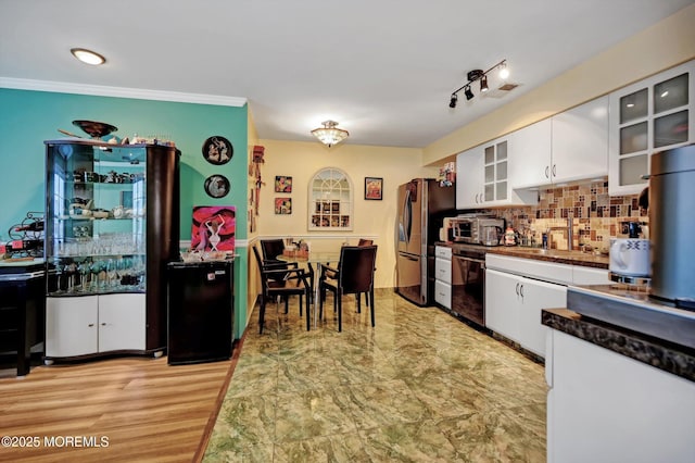 kitchen with white cabinetry, black dishwasher, sink, stainless steel fridge, and backsplash