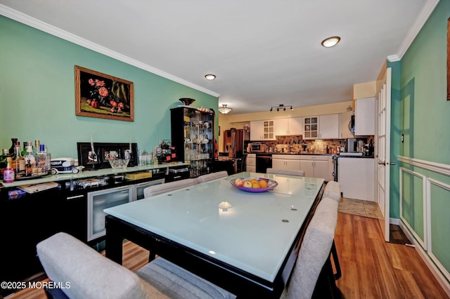 kitchen with white cabinetry, ornamental molding, light hardwood / wood-style floors, and decorative backsplash