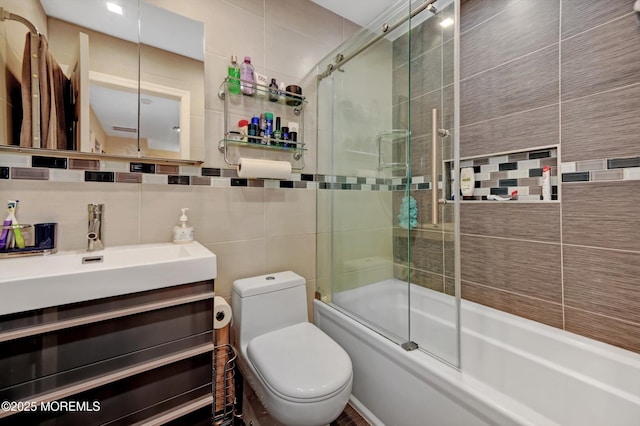 full bathroom with tile walls, decorative backsplash, enclosed tub / shower combo, vanity, and toilet