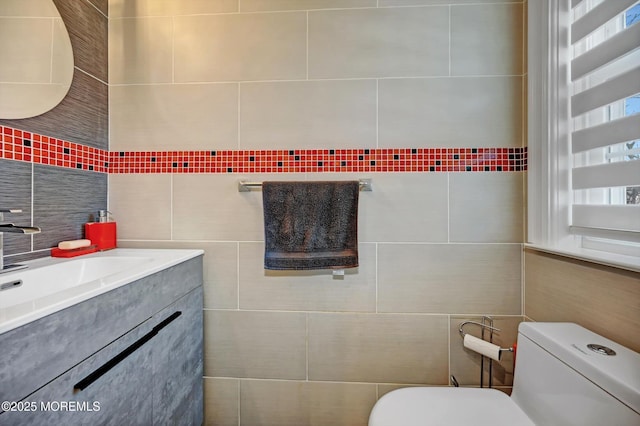 bathroom with vanity, toilet, and tile walls