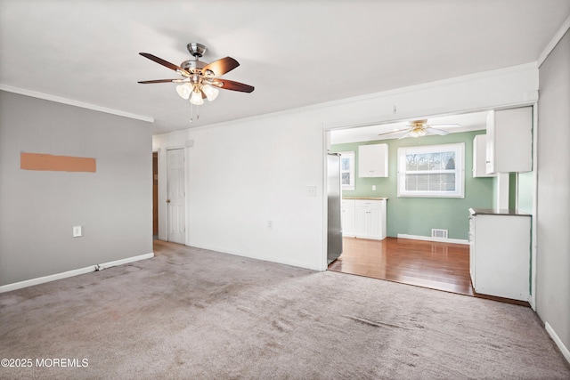 spare room with crown molding, ceiling fan, and carpet flooring