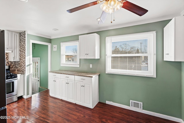 kitchen with dark hardwood / wood-style floors, white cabinetry, backsplash, stainless steel gas range oven, and a healthy amount of sunlight