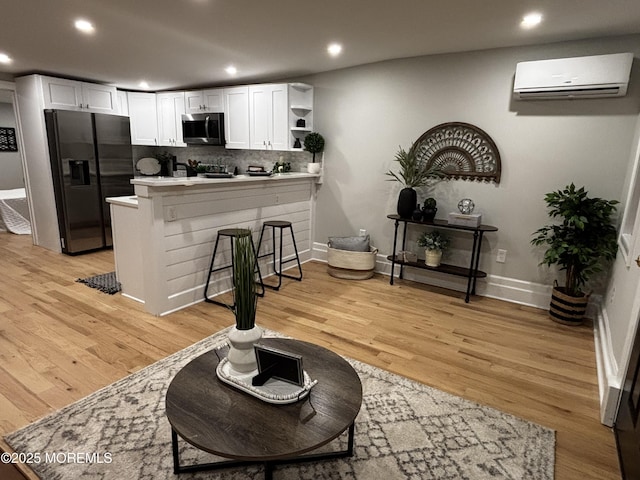 kitchen with white cabinetry, a wall mounted air conditioner, a kitchen bar, black refrigerator with ice dispenser, and kitchen peninsula