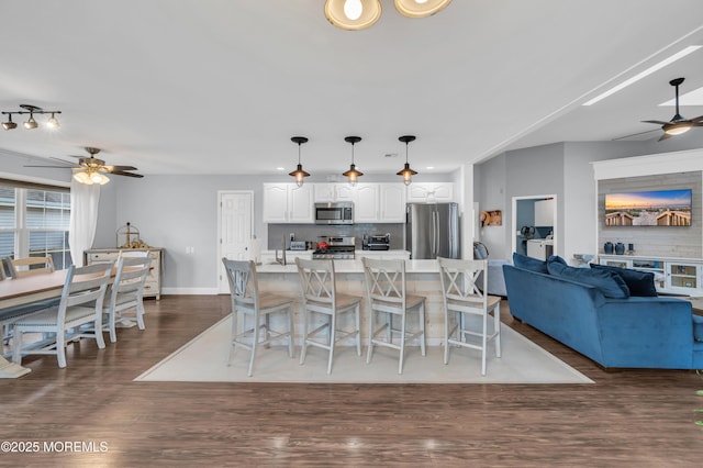 kitchen featuring white cabinetry, tasteful backsplash, a center island with sink, pendant lighting, and stainless steel appliances