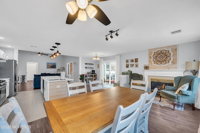 dining room with dark wood-type flooring, ceiling fan, and track lighting