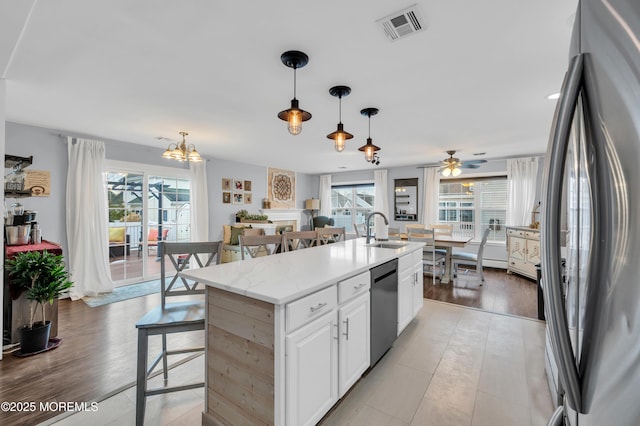 kitchen featuring appliances with stainless steel finishes, white cabinetry, hanging light fixtures, a center island, and plenty of natural light