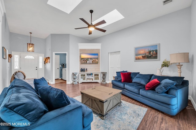 living room with ceiling fan, wood-type flooring, and lofted ceiling with skylight