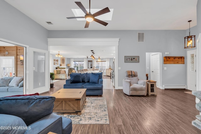 living room featuring baseboard heating, wood-type flooring, and ceiling fan with notable chandelier