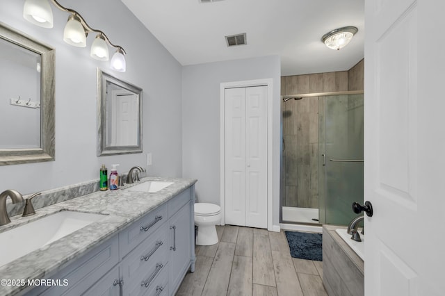 bathroom featuring a shower with door, vanity, and toilet