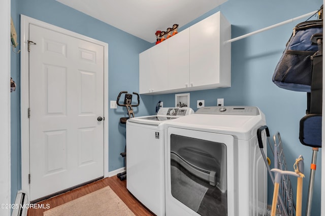 laundry room with baseboard heating, cabinets, wood-type flooring, and washing machine and dryer