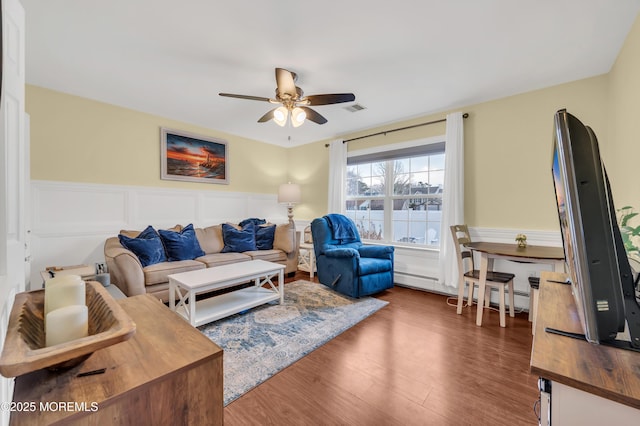 living room with ceiling fan, a baseboard heating unit, and dark hardwood / wood-style flooring