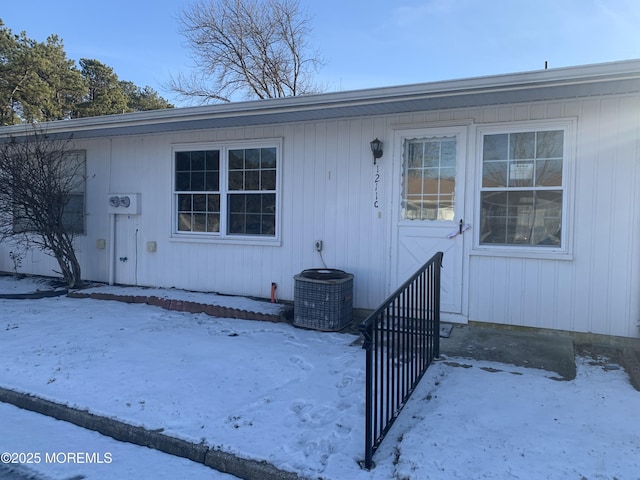 snow covered property entrance featuring central AC unit