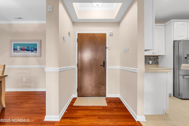 entryway featuring crown molding, light wood-type flooring, and a skylight