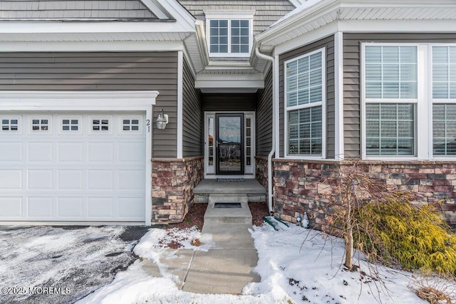 snow covered property entrance featuring a garage