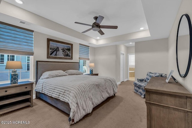 carpeted bedroom with ceiling fan, connected bathroom, and a raised ceiling